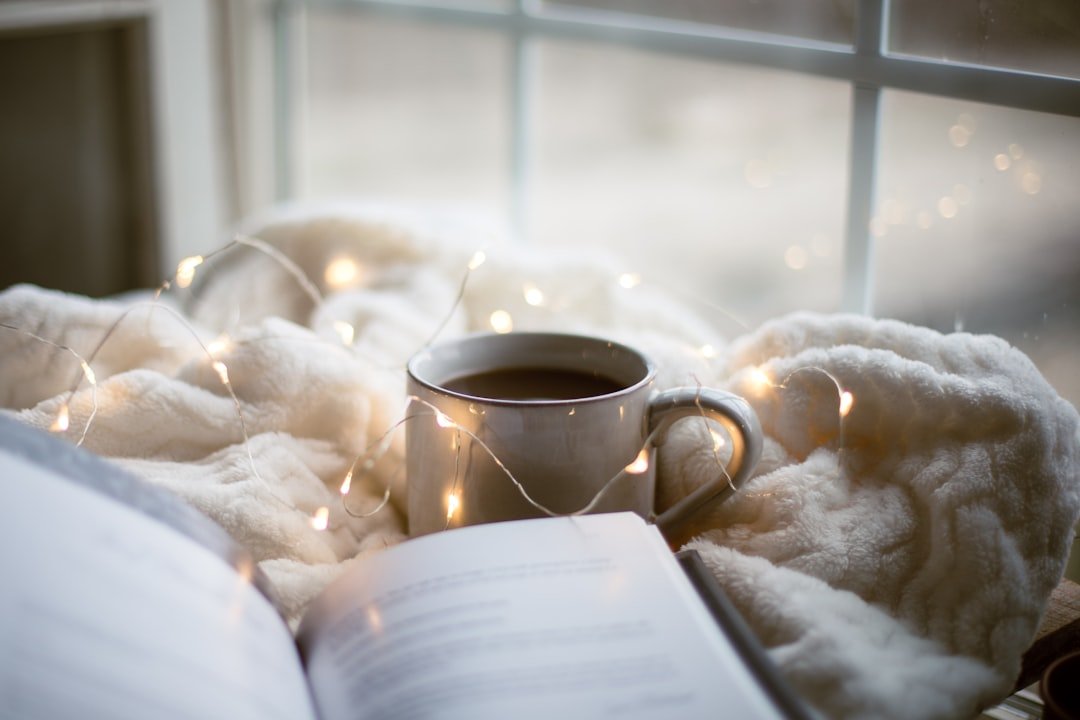 A book and coffee on a blanket for a cozy fantasy books reading guide